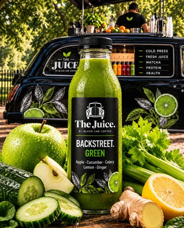 Backstreet Green juice in a black-labelled bottle, surrounded by fresh green produce in front of the branded Juice cab